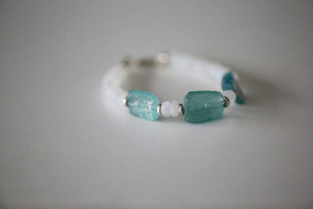 Close-up of a handcrafted aquamarine crystal bead bracelet on a neutral backdrop.