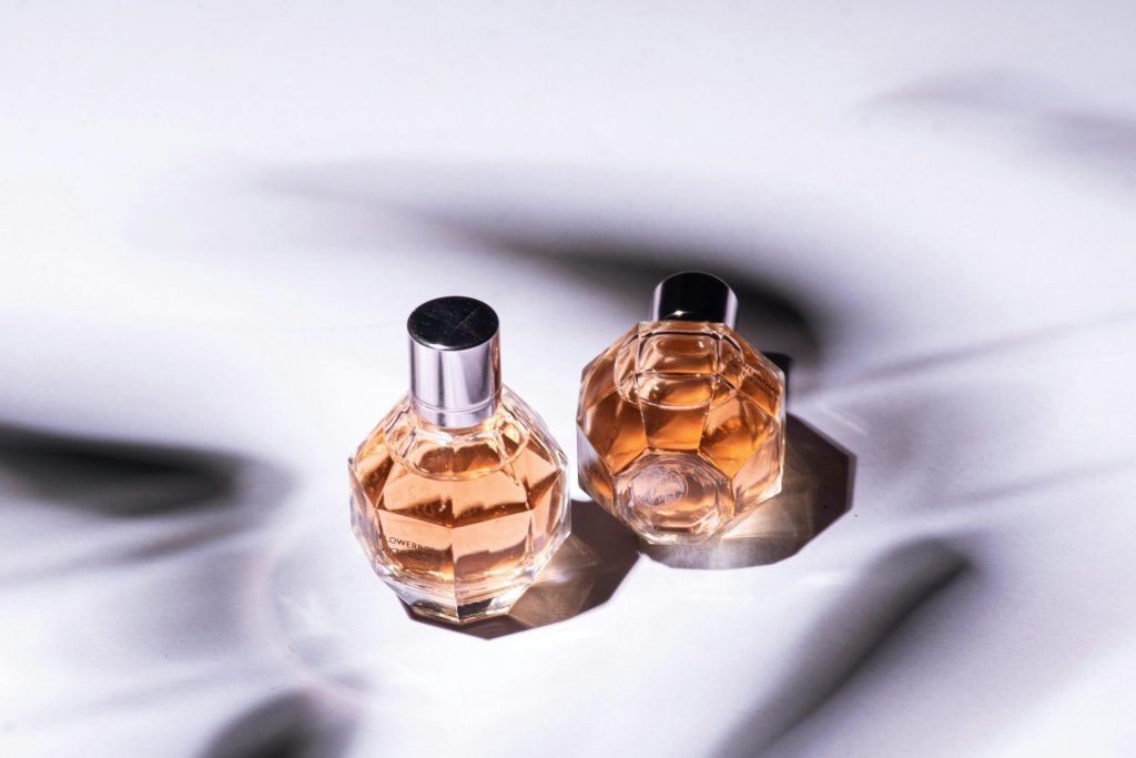 Close-up of two elegant perfume bottles casting artistic shadows on a soft surface.