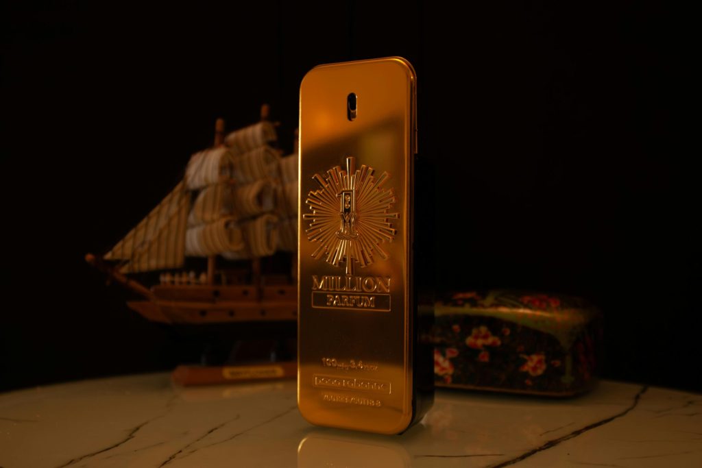 Elegant golden perfume bottle with a ship and floral box in the background.
