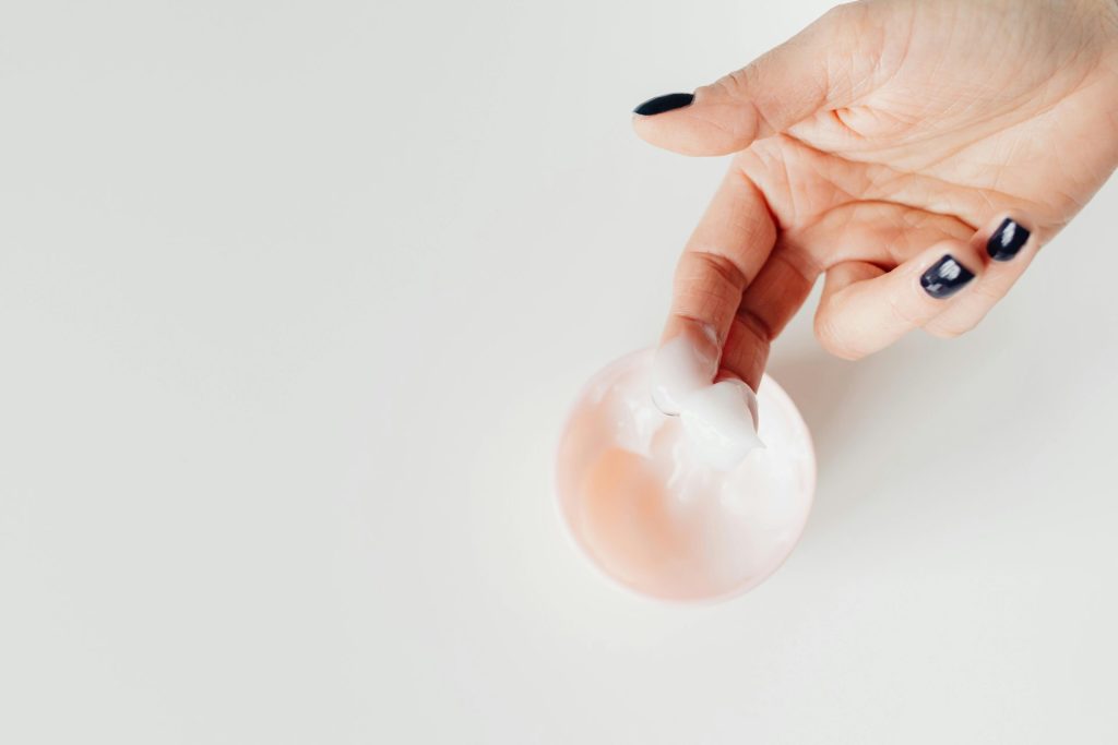 A close-up view of a hand applying cream with neatly manicured nails, perfect for skincare concepts.