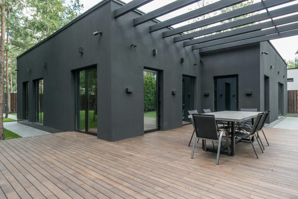 Contemporary black house with spacious wooden terrace and outdoor seating area.