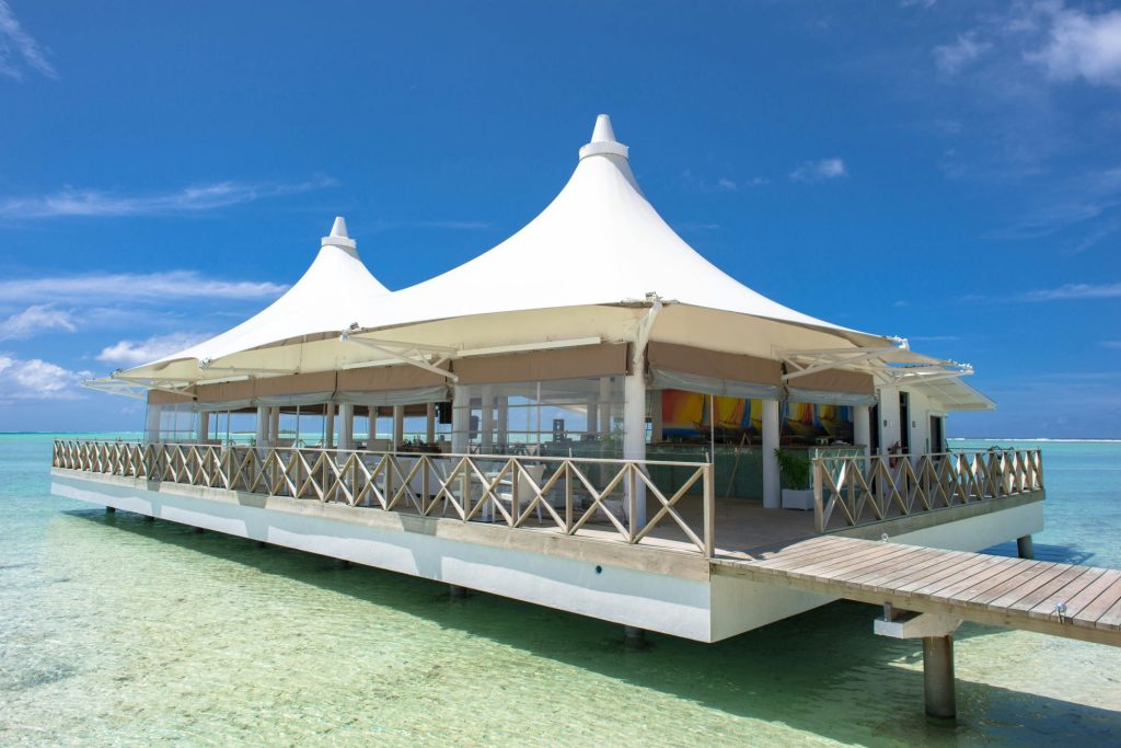 Beautiful overwater pavilion with white tent roof on clear turquoise water in Maldives.